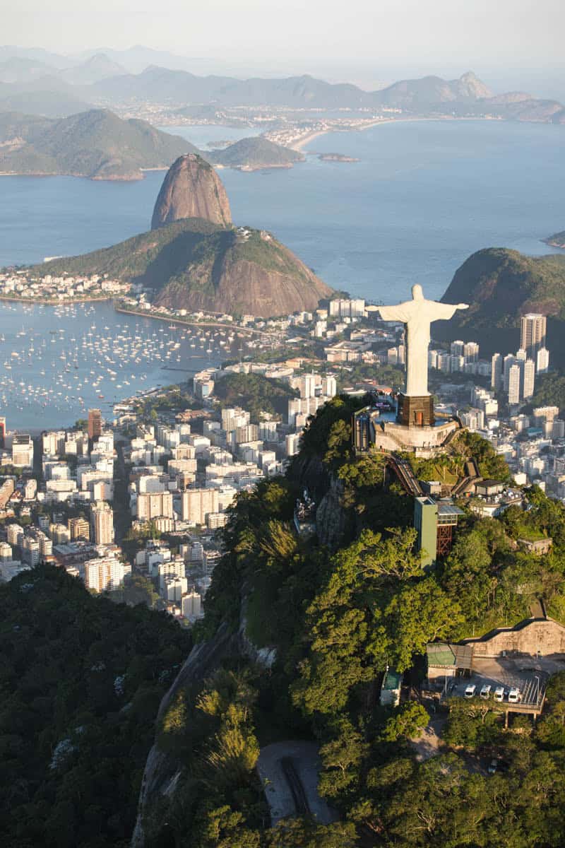 Christ the Redeemer stands above Rio de Janeiro, Brazil, with Sugarloaf Mountain and Guanabara Bay behind it.